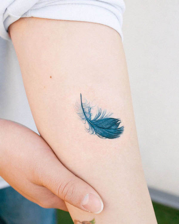 Tiny blue feather tattoo by @hansantattoo