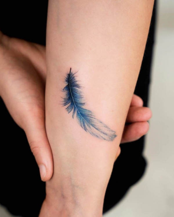 Small blue feather wrist tattoo by @_rony_tattoo