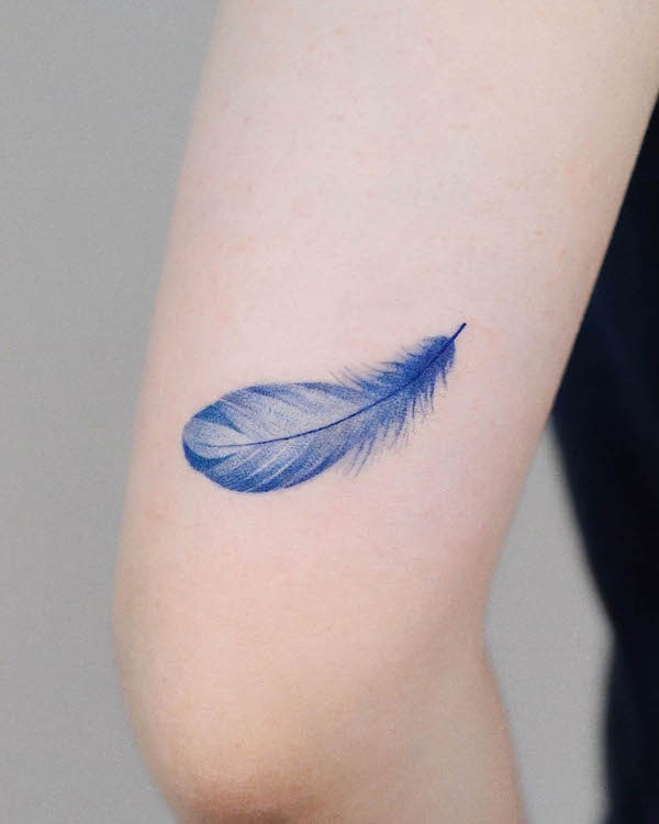 Light and airy blue feather arm tattoo by @zihong_tattoo
