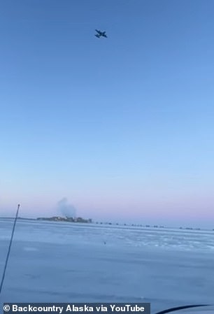 A military aircraft flies over the frozen Alaska landscape towards where the objects crashed